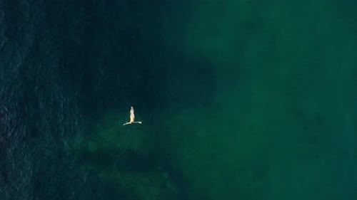 Top View of a Woman in a Yellow Swimsuit Swimming in the Sea with Clear Water