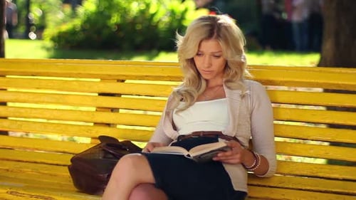 Young Adult Woman Girl Reads Book in Park Yellow Bench Waiting