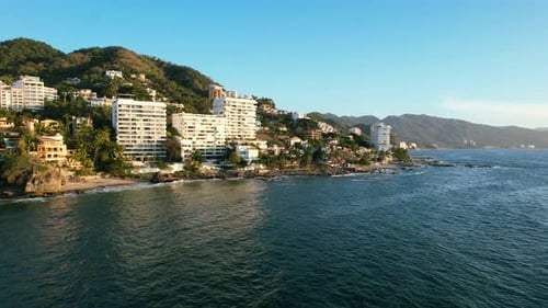 Hotels and resorts on oceanfront mountain hill at golden hour sunset at Los Muertos Beach in Puerto