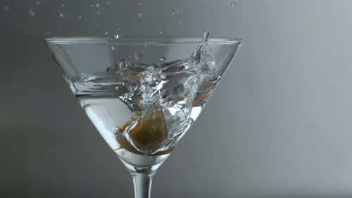 Olive Dropped Into Classic Clear Martini Glass