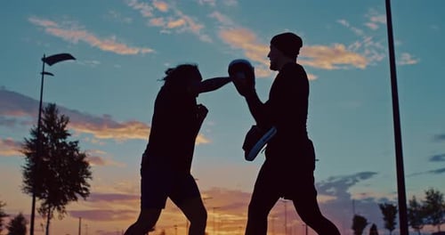 Silhouettes of Black Fighter and His Coach During Outdoor Workout in Sunset Time Prores
