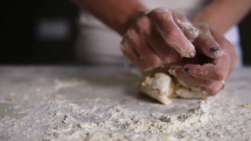 Closeup View of Woman's Hands Kneading Dough in Flour on the Table