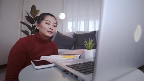 Geschäftsfrau auf Redshirt nutzt den Laptop, um sich online zu treffen und von zu Hause aus zu arbeiten