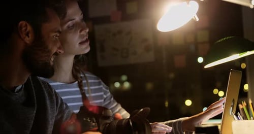 Colleagues Reviewing Photography on Laptop at Night