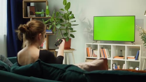 Woman Watching TV with Green Screen in Living Room Back View