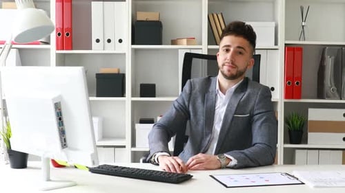 Junger Geschäftsmann am Arbeitsplatz blickt in die Kamera