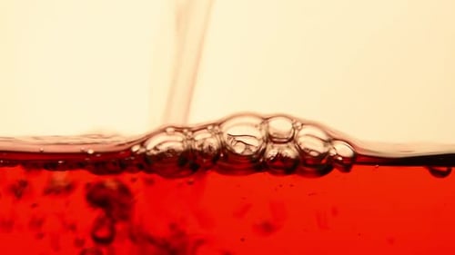 Red black tea pouring in glass teapot close up
