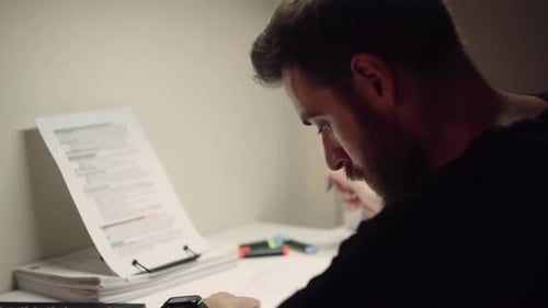 A Bearded Man Seriously Studying At Home, Copying And Highlighting Notes - close up