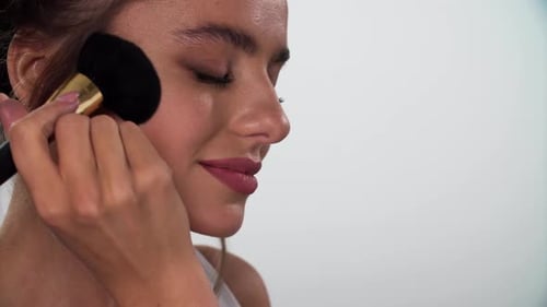 Gesichts-Make-up. Nahaufnahme von Frau, die Rouge mit Kosmetikpinsel
aufträgt