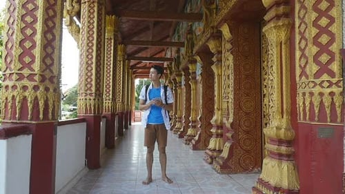 Man Walking In Temple And Looking At Smartphone