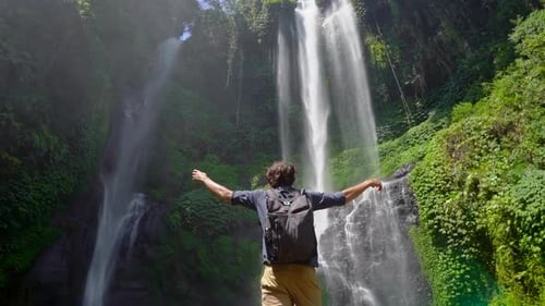 Young Man Tourist Visits the Biggest Waterfall on the Bali Island - the Sekumpul Waterfall