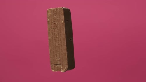 A Delicious and Unhealthy Chocolate Bar Rotates on a Pink Background. Bitten Sweets Isolated. The