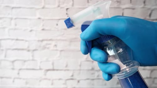 Hand in Glove Squeezing a Spray Bottle