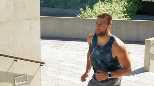 Young Man in Earphones Running Upstairs Outdoors