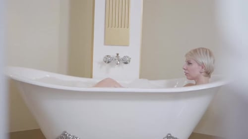 Gorgeous Blond Woman Relaxing in Bathtub. Side View of Adult Caucasian Lady Lying Down in Bath with