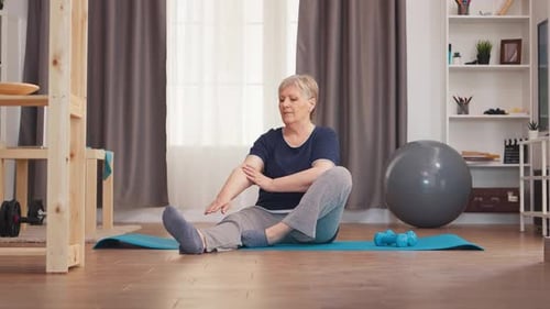 Senior Woman Stretching on Yoga Mat in Living Room