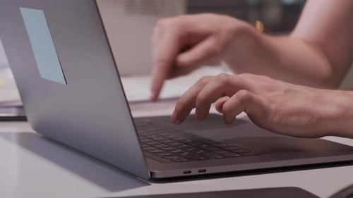 Close Up Male Hands Fingers Typing on the Keyboard Using a Computer Laptop in a Dark Office