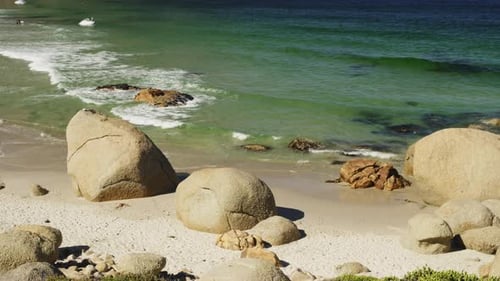 Des vagues douces s'écrasent sur un rivage rocheux par un matin ensoleillé