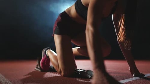 Professionelle Sportlerin auf dunklem Hintergrund Gotovtes, um den Sprint der Joggingschuhe zu laufen