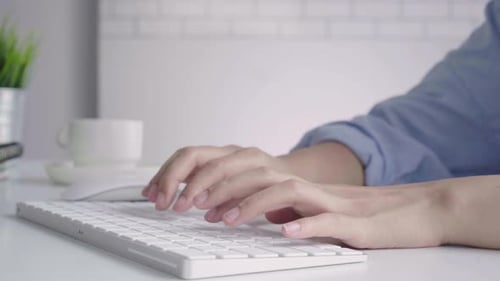 young smiling Asian woman working on laptop while at home in office work space.