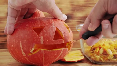 Hands Carving an Orange Pumpkin for Halloween