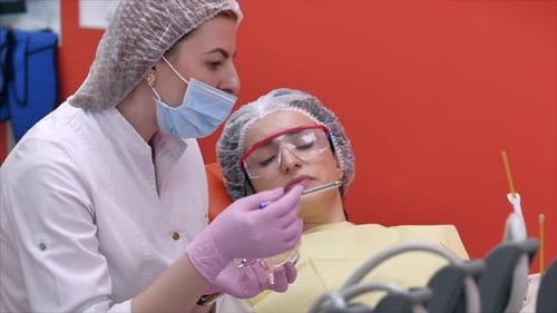 Woman Dentist Treating Teeth To Woman Patient in Clinic.Dentist Shows the Patient on the Model
