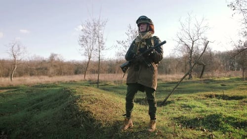 Young Pretty Redhead Woman in Military Uniform Armed with Rifle at the Battlefield Area