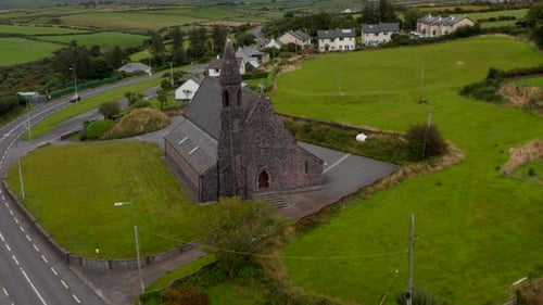 Pull Back Footage of Old Stone Church Standing at Road in Village in Countryside