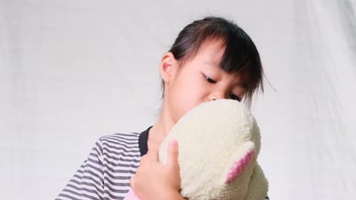 Child Hugging Stuffed Animal in Front of Background