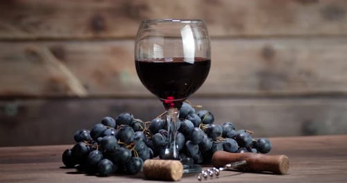 The Glass of Red Wine on the Table Slowly Rotates. On a Wooden Background