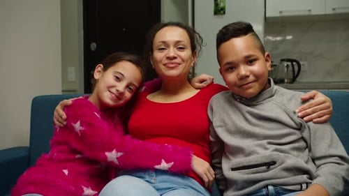 Smiling Woman with Children Sitting on Couch Indoors
