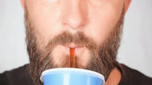 Man Drinks Refreshing Beverage with Straw, Close Up