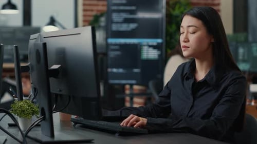 Porträt eines lächelnden asiatischen Programmierers, der sich auf das Schreiben von Code am Schreibtisch konzentriert