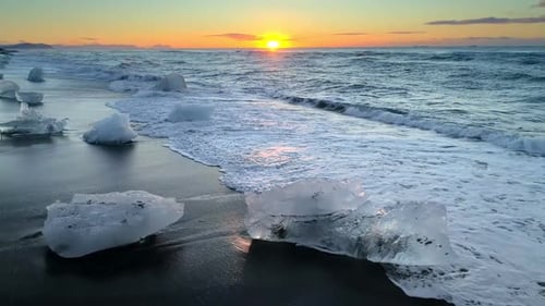 La glace d'un glacier se lave par les vagues de l'océan Atlantique sur une plage de Black Diamond en Islande. Mondial