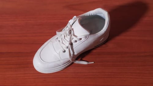 Single White Shoe Close-Up on Wooden Surface
