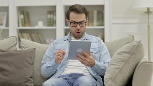 Excited Man Celebrating Success Using Tablet Indoors