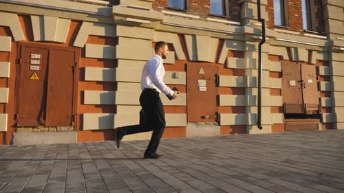 Jovem empresário com maleta correndo ao longo da rua da cidade