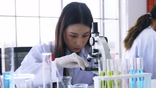 Female Scientist Uses Microscope in a Lab