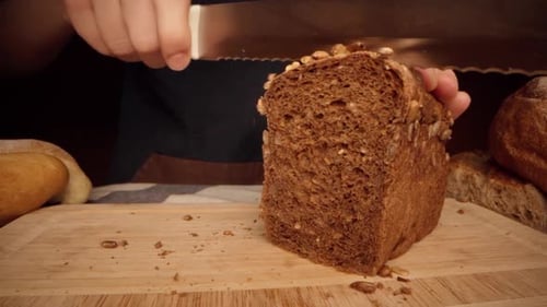 Slicing Brown Bread Loaf on Wooden Board