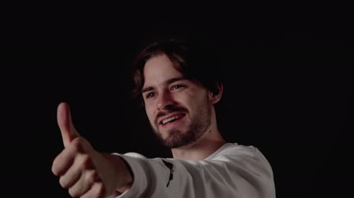 Trendy Young Man giving thumbs up, appreciative reaction, close, black background