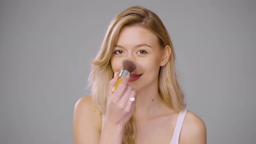 Young Woman with Brush Applying Makeup