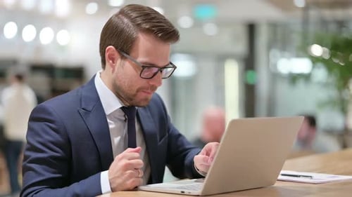 Businessman Celebrates Success Working on Laptop