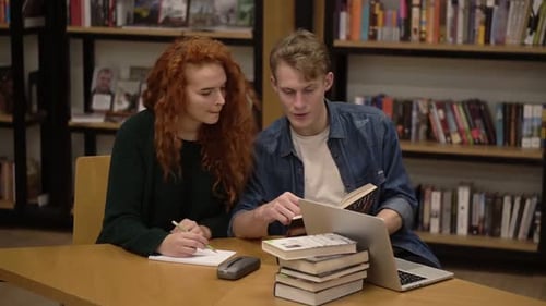 Red Headed Girl and Handsome Guy European Students Study Together Read Book in Students Library