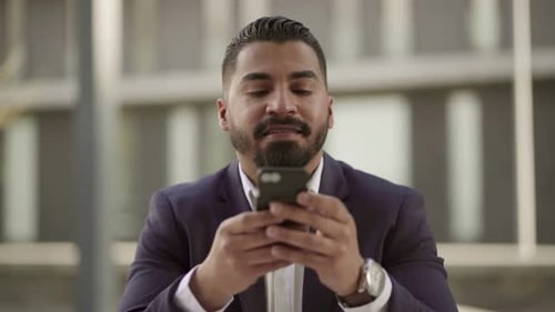 Man in Suit Using Phone and Smiling