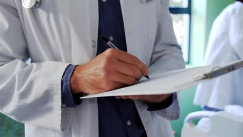 Médecin de sexe masculin écrivant sur un bloc-notes dans le service 4k