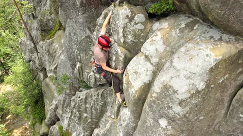 Determined Climber Clambering Up Steep Wall of Rocky Mountain