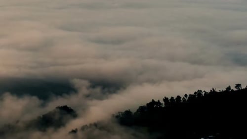 Mountain Side Peeks Through Thick Layer of Clouds