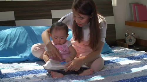 Mother and Baby Reading Together on Bed