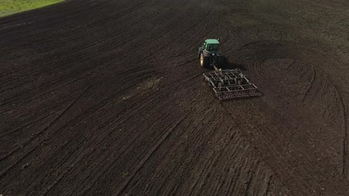 Tractor plows the ground with a plow in the field