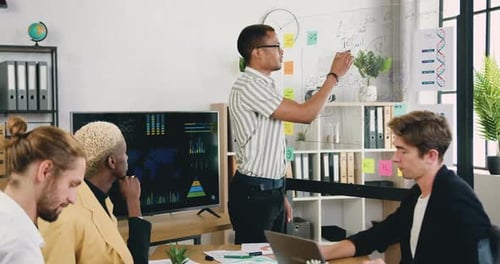 Équipe masculine créative et diversifiée assise sur le lieu de travail et écoutant l'explication